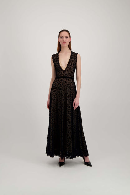 Jeune femme rousse habillée d'une longue robe du soir en tulle et velours noir avec un grand décolleté en V.