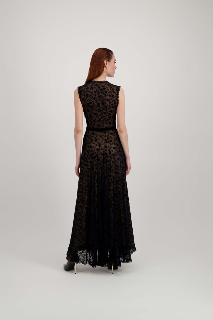 Jeune femme rousse de dos habillée d'une longue robe du soir en tulle et velours noir avec un grand décolleté en V.