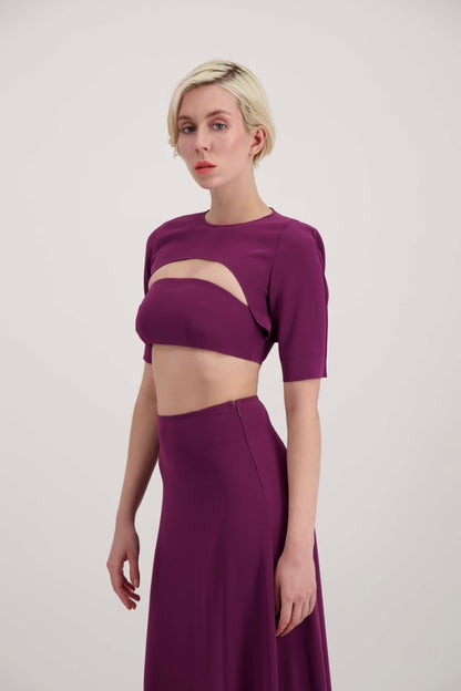 Femme blonde de profil habillée d'un ensemble avec un boléro, un bandeau et une jupe fendue lila