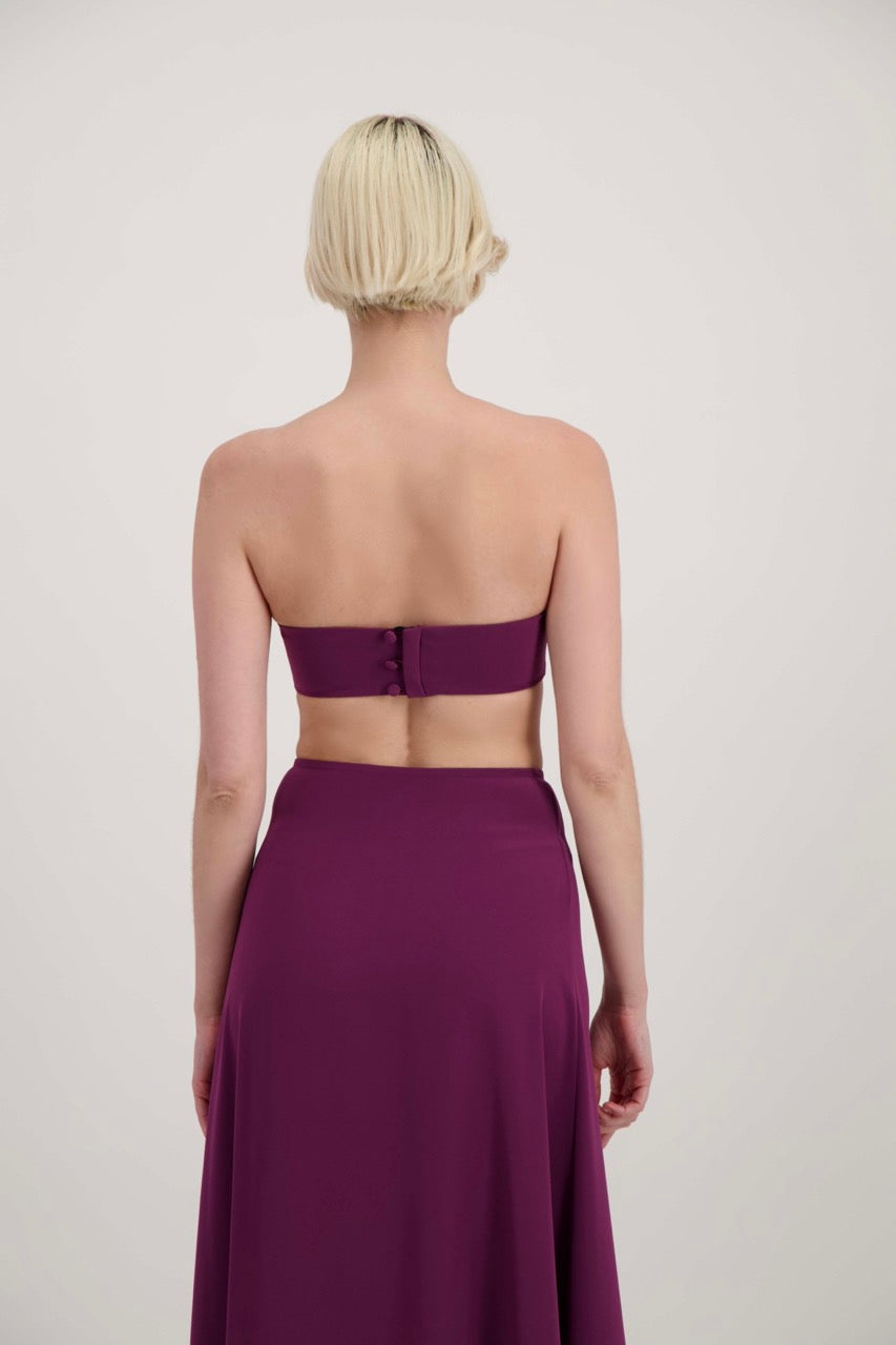 Femme blonde de dos habillée d'un ensemble lila avec un bandeau et une jupe