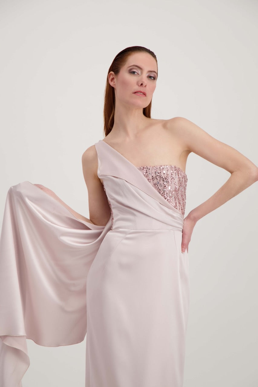 Jeune femme rousse habillée d'une longue robe rose avec un bustier pailleté et une étole qui finit en traîne