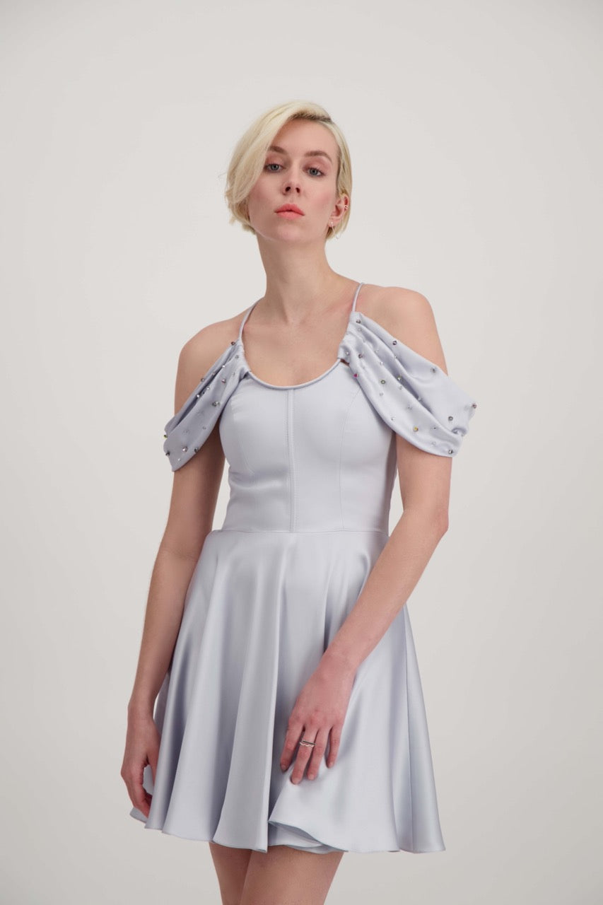 Jeune femme blonde habillée d'une robe coktail courte de couleur argent avec des strass sur les épaules
