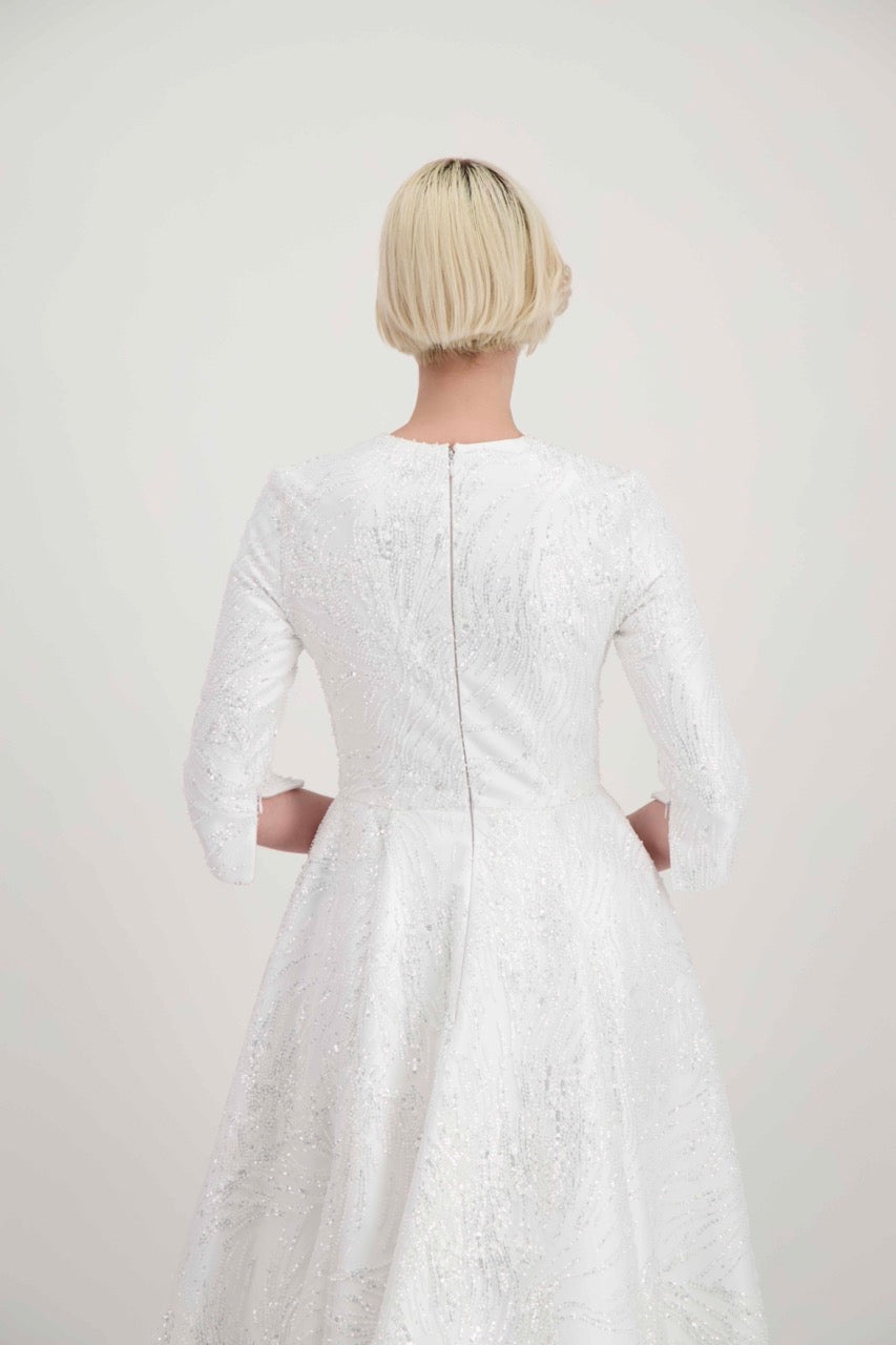 Jeune femme blonde de dos habillée d'une robe de mariée avec des manches 3/4