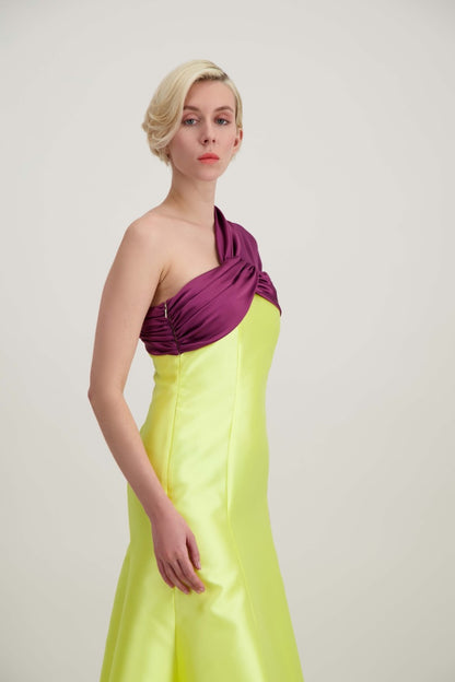 Jeune femme blonde de profil habillée d'une robe longue du soir asymétrique en violet et jaune