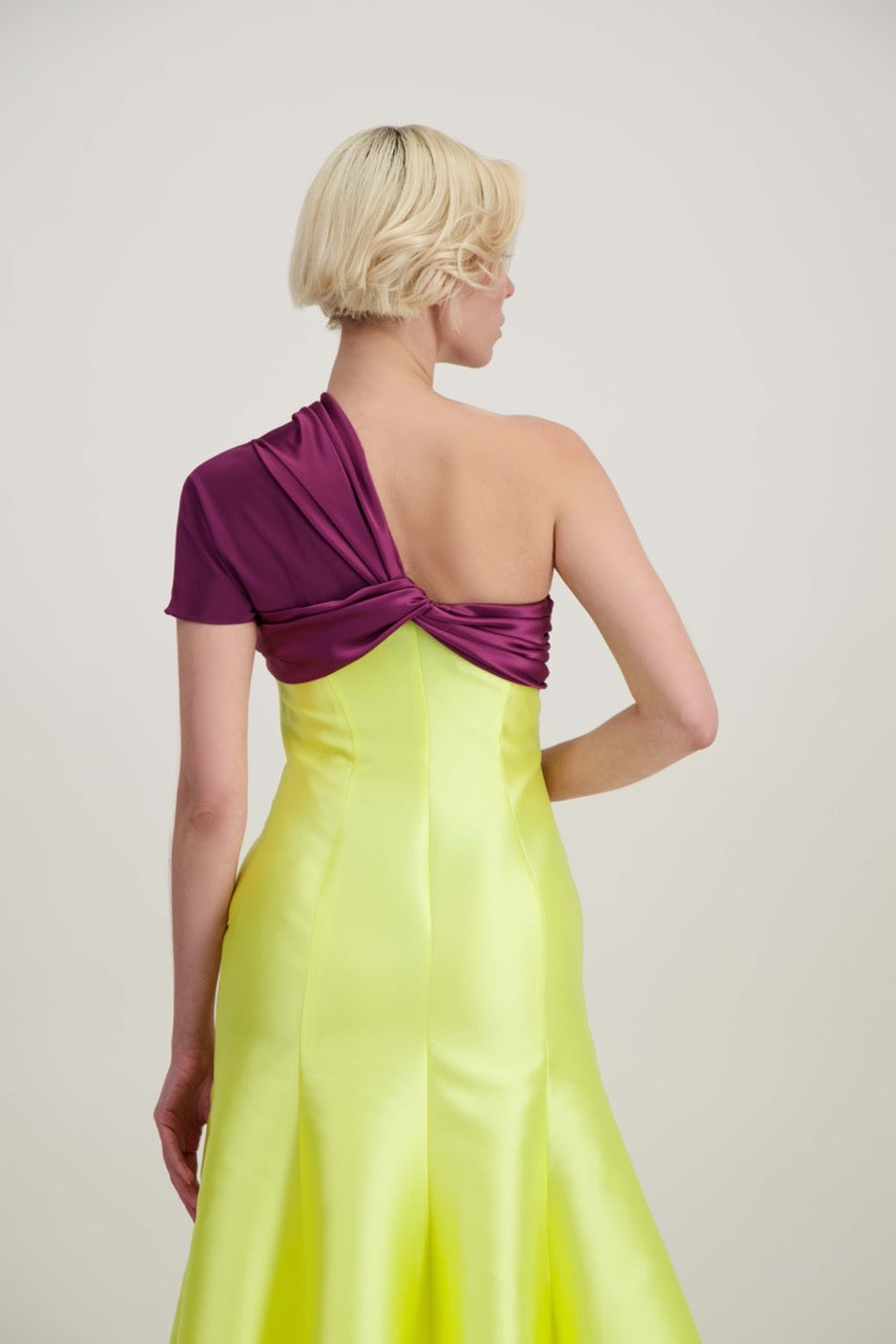 Jeune femme blonde de dos habillée d'une robe longue du soir asymétrique en violet et jaune
