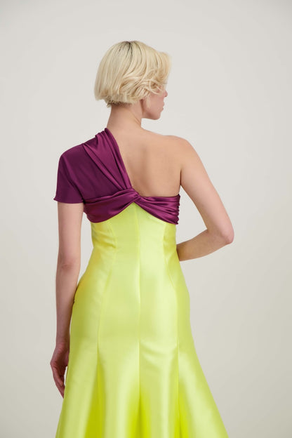 Jeune femme blonde de dos habillée d'une robe longue du soir asymétrique en violet et jaune