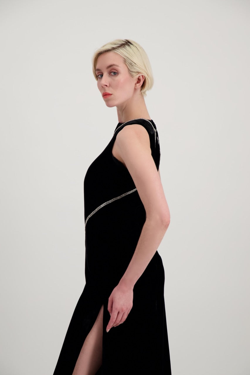 Jeune femme blonde de profil habillée d'une robe longue en velours noir avec des chevrons de strass et une fente
