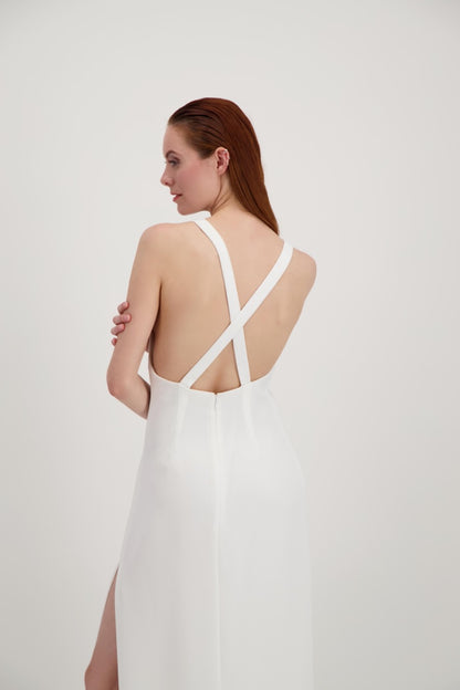 Jeune femme rousse habillée d'une longue robe blanche avec un dos nu ouvert sur des bretelles qui se croisent