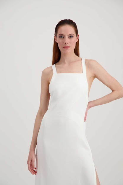 Jeune femme rousse habillée d'une longue robe blanche à larges bretelles avec une grande fente