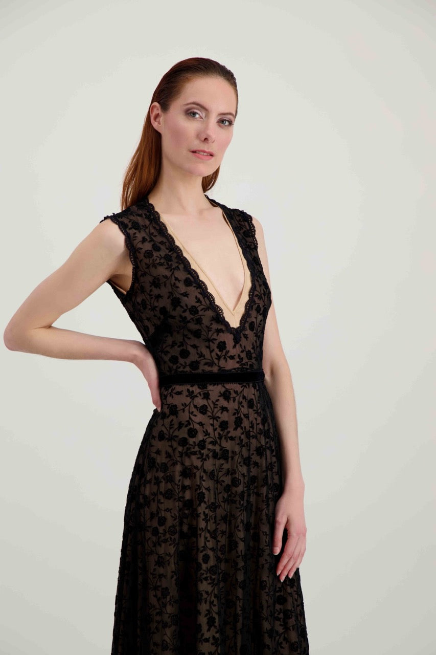 Jeune femme rousse de profil habillée d'une longue robe du soir en tulle et velours noir avec un grand décolleté en V.