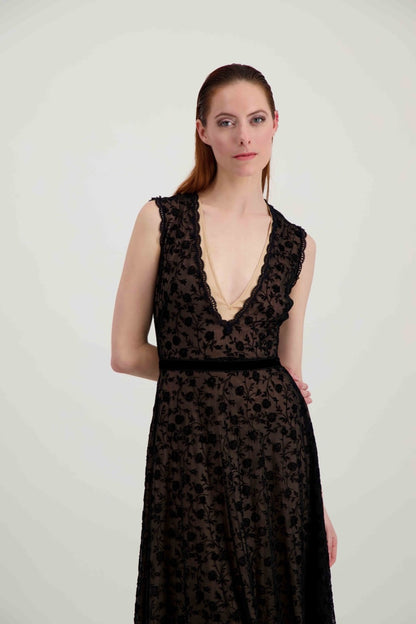 Jeune femme rousse habillée d'une longue robe du soir en tulle et velours noir avec un grand décolleté en V.